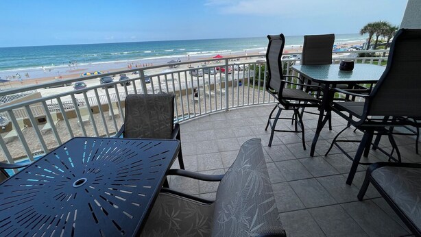 Ein Balkon mit Blick auf den Strand, ausgestattet mit Sitzgelegenheit und einem Tisch.