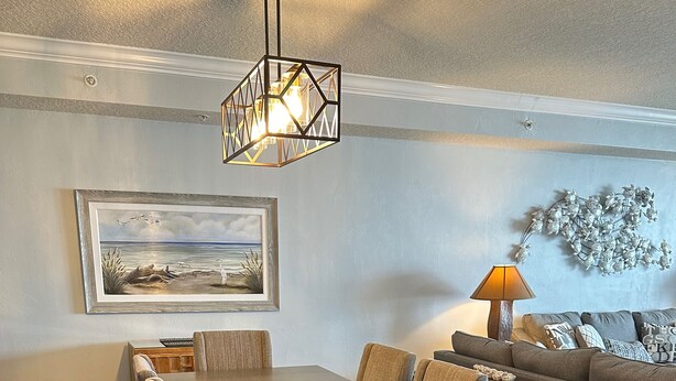Ein Essbereich mit einem Holztisch und Stühlen, einer Couch, einer Lampe und einem Gemälde an der Wand.