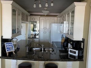 A kitchen with white cabinetry, a black countertop, and a coffee station.