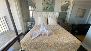 Un lit bien fait, recouvert d’une couvre-lit à motifs floraux, avec une tête de lit blanche et une paire de serviettes blanches.