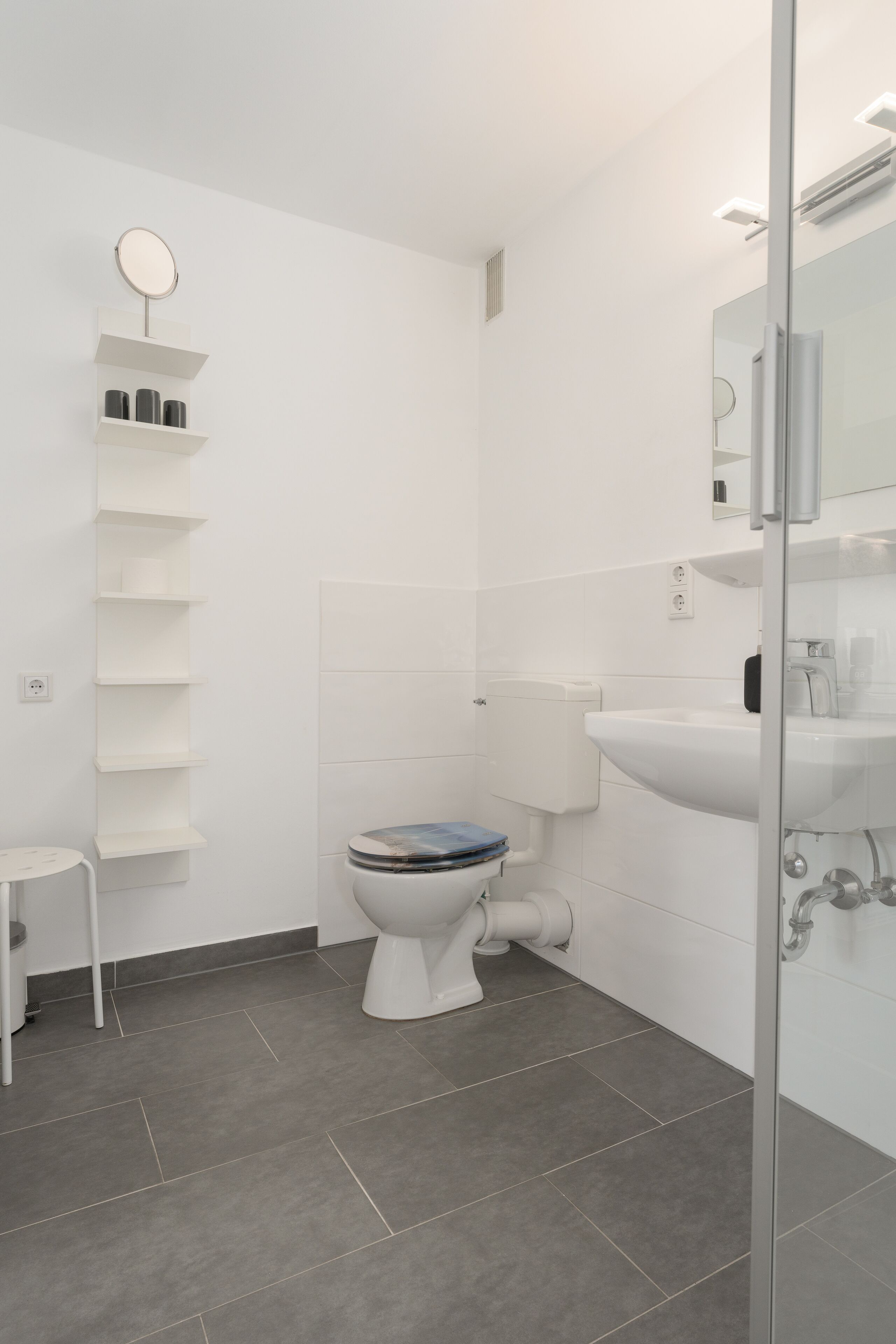 Une salle de bain moderne avec des toilettes, un lavabo et un miroir.