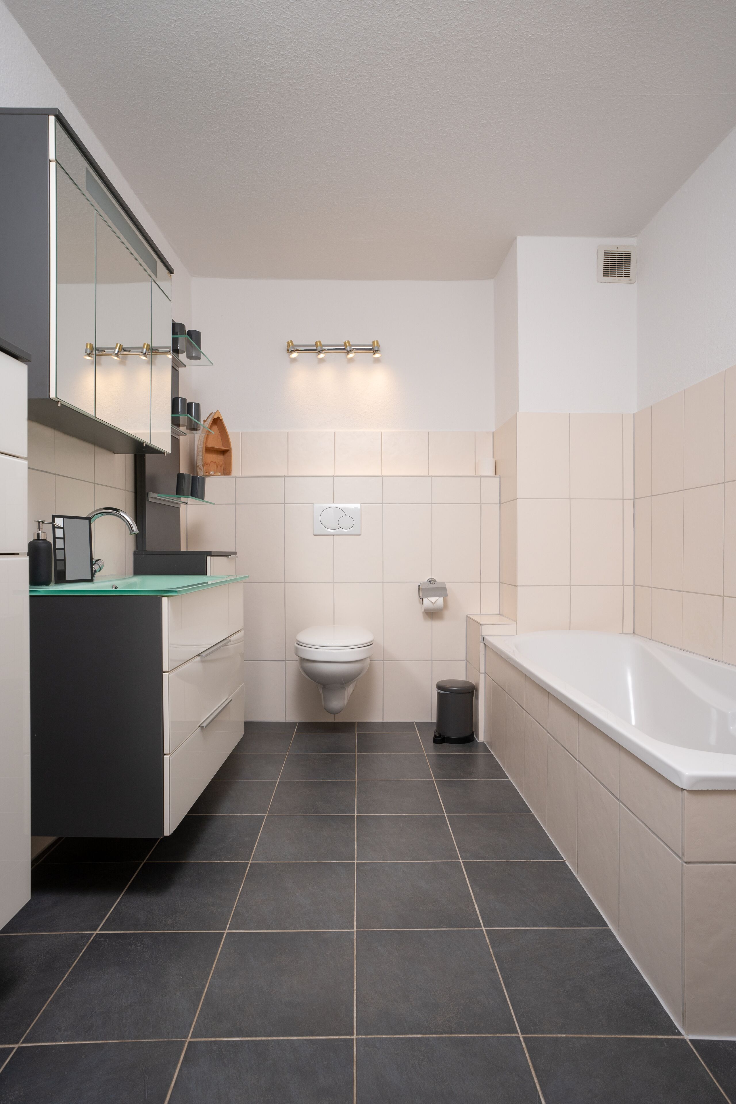 A modern bathroom with a glass sink, a toilet, and a bathtub.