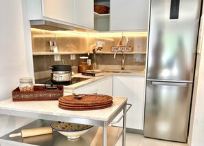 Une cuisine moderne équipée d’un réfrigérateur en acier inoxydable, d’un four encastré et d’un livre de recettes posé sur le plan de travail.