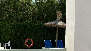 A poolside area with a lounge chair, a hat, and a book on a table. - Cielo 103. Upper Ground Floor, Pool View. (Pollença)
