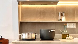 A kitchen with a stove, two pots, a bottle of oil, and a spice rack. - Cielo 103. Upper Ground Floor, Pool View. (Pollença)