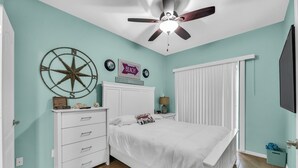 Un dormitorio con una cama, un aparador, un ventilador de techo y un reloj de pared.