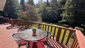 A deck with a round table and chairs, surrounded by a wooden railing. - Private mid-century modern hideaway in forest near the river and sea. (Crescent City)