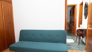 A room with a teal sofa, wooden wardrobe, and a small table with a mirror. - White Heaven. Near the Marina Lakki and a Wonderful View of the Port. (Leros)