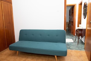 Une pièce avec un canapé de couleur turquoise, une armoire en bois et une petite table avec un miroir.