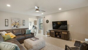 A modern living room with a sectional sofa, a flat-screen TV, and a ceiling fan. - Jenks Spectacular Spain Ranch-Close to Five Oaks (Jenks)