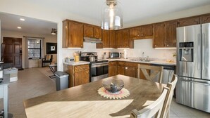 A modern kitchen with wooden cabinets, stainless steel appliances, and a central island with seating. - Jenks Spectacular Spain Ranch-Close to Five Oaks (Jenks)