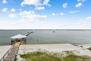 A beach with a wooden pier leading to a covered structure, a calm sea, and a clear sky. - My Forever Coconut ! Dog Friendly on the water! (Navarre)