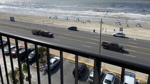 A beach view with a road, parked cars, and beach umbrellas. - Galveston Oceanview,Wonderful location! 2bed/2bath (Galveston)
