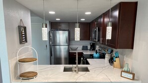 A modern kitchen with a central island, stainless steel appliances, and pendant lighting. - Galveston Oceanview,Wonderful location! 2bed/2bath (Galveston)