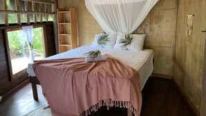 A room with a bed, a canopy, a wooden shelf, and a window with a view of greenery. - Unah Piracanga (Maraú)