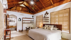 A bedroom with a wooden ceiling, a bed with multiple pillows, a nightstand, a mirror, and a window with blinds. - Bungalow Armonia - Perfect Getaway! (North Santa Teresa)