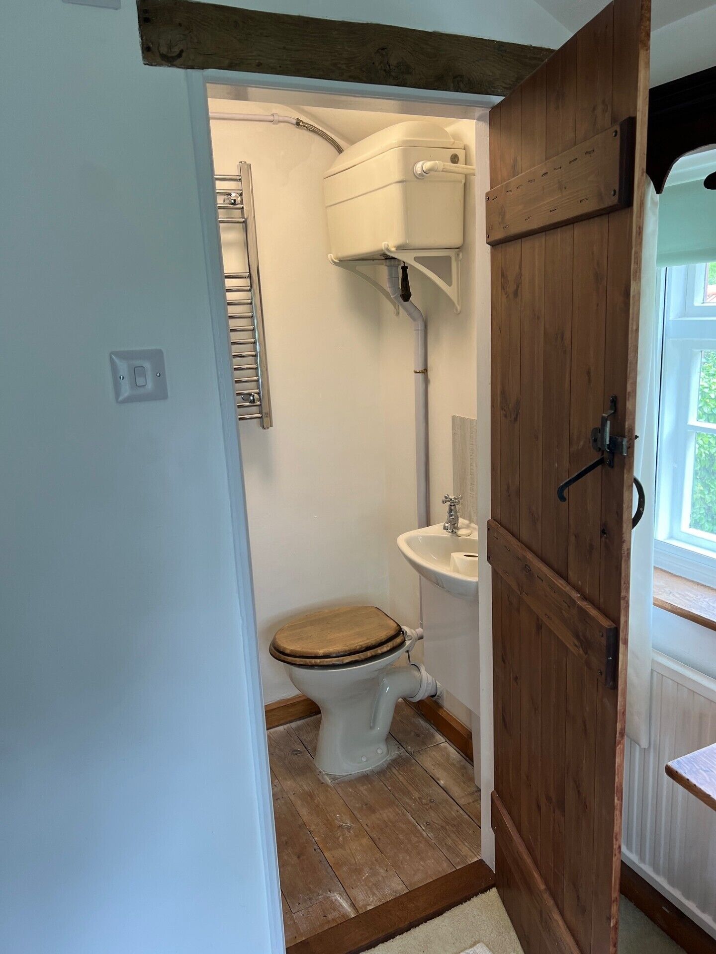A compact bathroom with a toilet, sink, and wooden door.