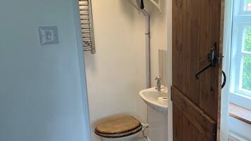A compact bathroom with a toilet, sink, and wooden door.