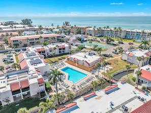 Um resort com piscina central, vários edifícios e vista para o oceano.