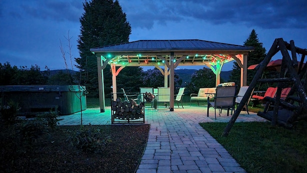 Un espacio al aire libre cubierto con una pérgola, un hogar y una pila de leña.