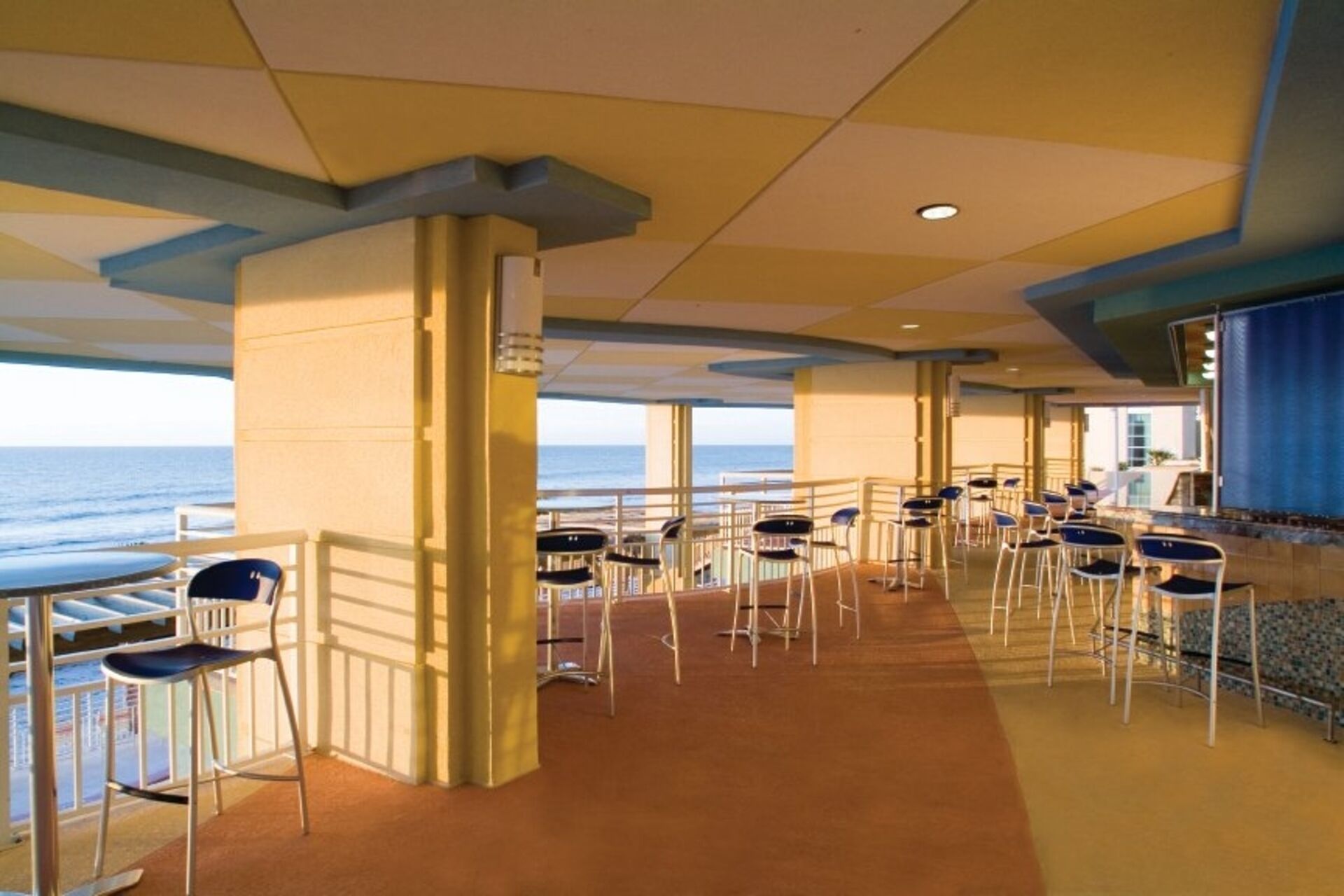 Une terrasse aménagée avec des tables et des chaises, offrant une vue sur l’océan.