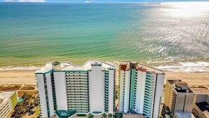 A beachfront hotel with multiple high-rise buildings, a sandy beach, and the ocean in the background.