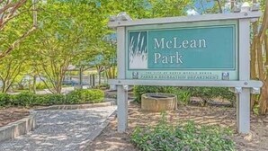 En skylt för McLean Park med fri sikt över den omgivande grönskan och en gångväg som leder till parkens entré.