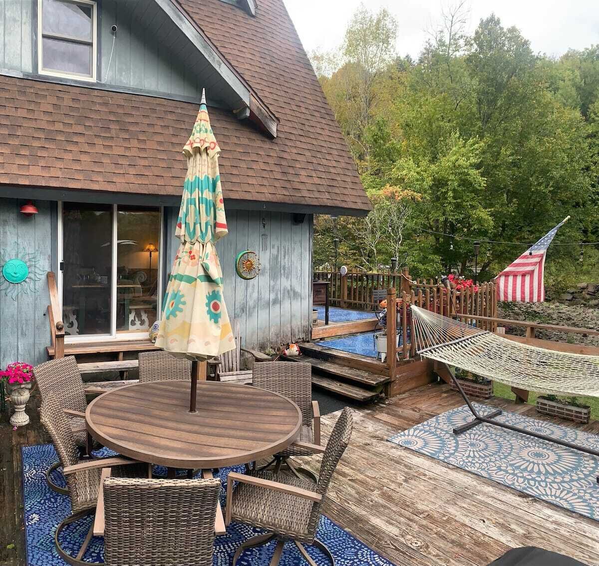 Eine Holzterrasse mit rundem Tisch, Korbstühlen, einer Hängematte und einer amerikanischen Flagge.