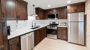 A modern kitchen with wooden cabinets, stainless steel appliances, and a white countertop.