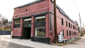 A red brick building with large windows and a black awning. - Mountain Home Theme: Suites of Lava #4 (Lava Hot Springs)