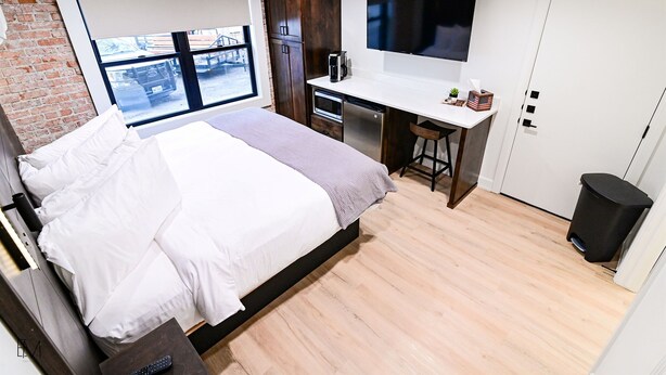 A modern hotel room with a large bed, a desk with a computer, a TV, and a view of the outside. - Mountain Home Theme: Suites of Lava #4 (Lava Hot Springs)