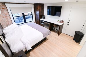 Ett modernt hotellrum med en stor säng, ett skrivbord med en dator, en TV och utsikt över omgivningarna.