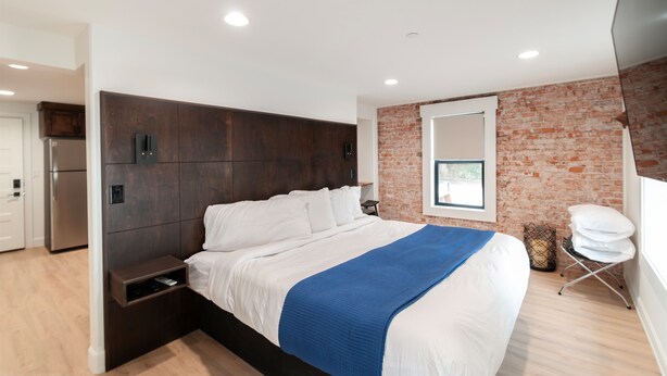 Un dormitorio moderno con una cama grande, una pared de ladrillo y una ventana.