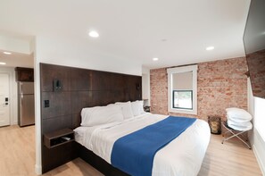 Une chambre moderne avec un grand lit, un mur en briques et une fenêtre.