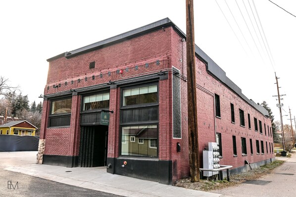 Un edificio de ladrillo rojo con amplias ventanas y un toldo negro.