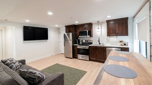 Una cocina moderna con armarios de madera, electrodomésticos de acero inoxidable y un comedor con una mesa grande y taburetes.