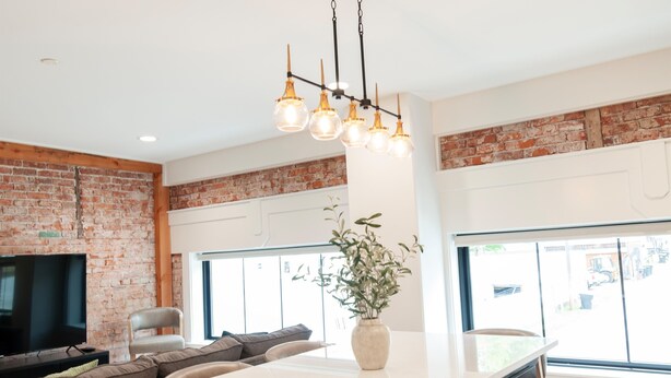 Een moderne keuken met een bakstenen muur, een groot eiland en een hanglamp.