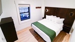 A bedroom with a bed, a window, a ceiling fan, and a small bedside table.