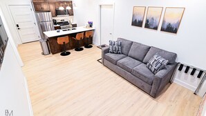 Une cuisine moderne avec un îlot central, un canapé gris et trois tableaux encadrés accrochés au mur.