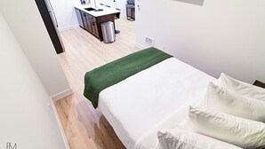 Une chambre à coucher avec un lit, un plaid vert et un mur blanc.