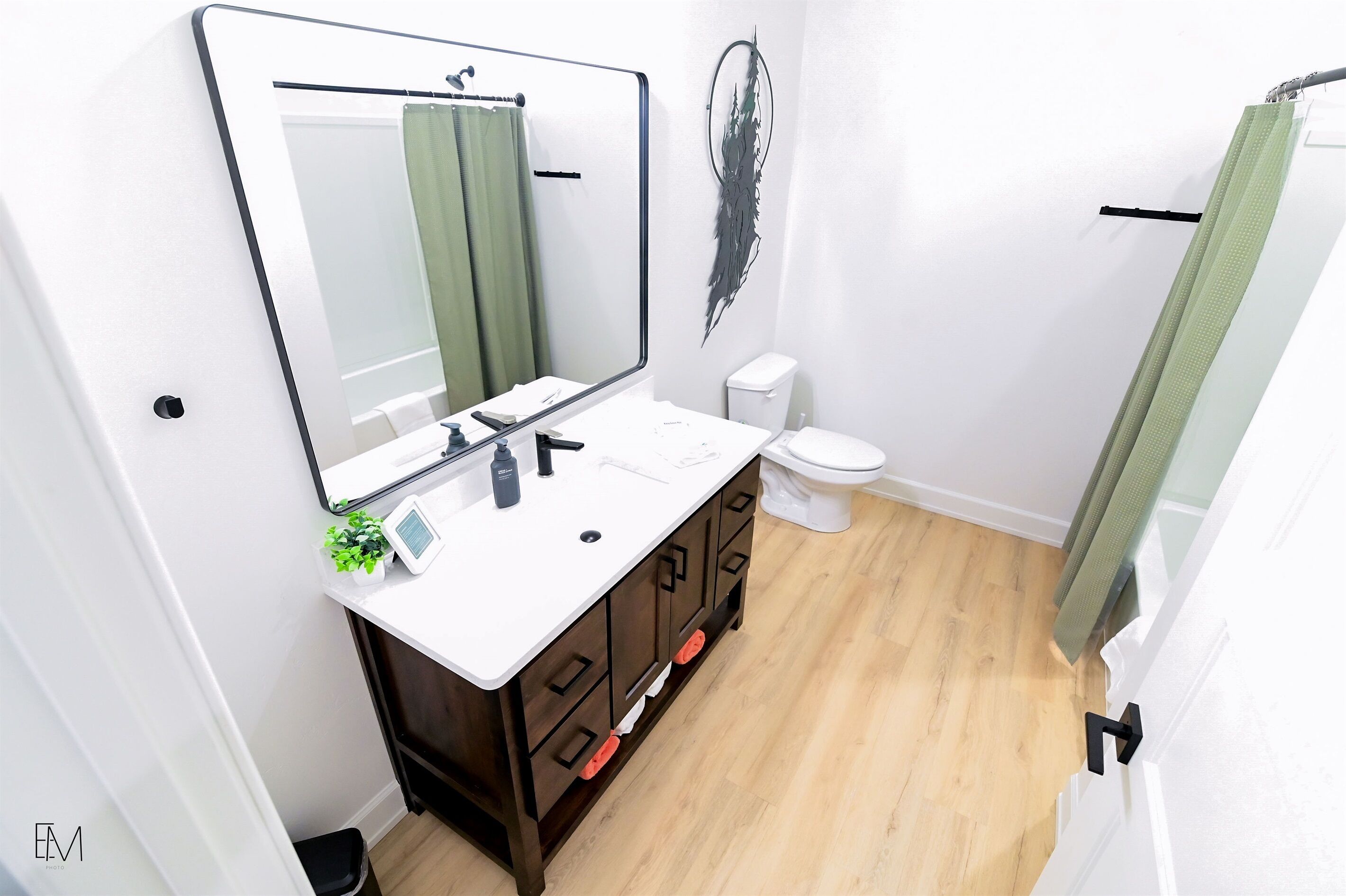 Une salle de bain avec un lavabo blanc, un meuble en bois foncé et un grand miroir.