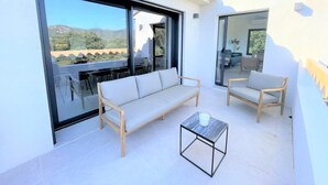 Un balcon avec un canapé, des chaises et une table en verre.