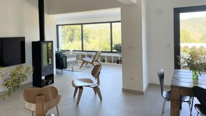 Un salon spacieux doté d’une cheminée, d’un téléviseur et d’un coin repas offrant une vue sur la verdure.