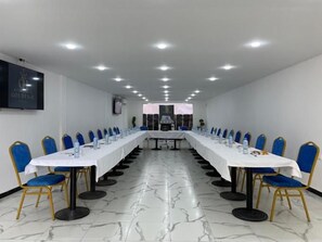 A conference room with a long table, blue chairs, and a white tablecloth. - Golden H Bejaia (Béjaïa)