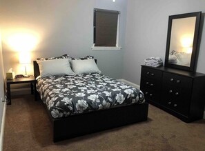 Restful retreat with a large bed, nightstand, dresser, and mirror.