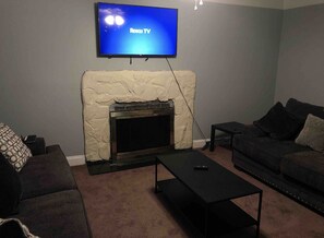 Cozy living room with a fireplace, flat-screen TV, and comfortable seating area.