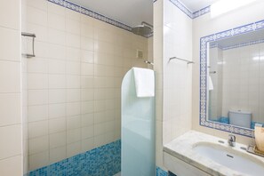A bathroom with a shower, a sink, and a mirror.
