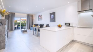 Une cuisine moderne dotée d’un îlot central, d’un coin repas avec une table et des chaises, et offrant une vue sur l’extérieur.