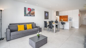 Un salon moderne avec un canapé gris, une table basse et un coin repas comprenant des chaises et une table.