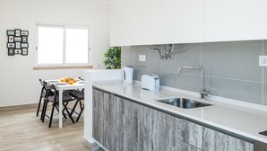 Una cocina moderna con una isla central, un lavamanos integrado y una zona de comedor con sillas y una mesa.